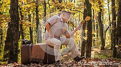Literature outside of library. getting knowledge and information from nature. Old man read sitting on retro suitcase Stock Photo
