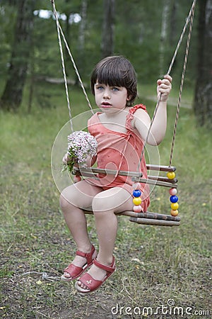 Litle cute girl sitting on swing. Stock Photo