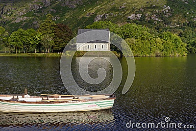 Litte boat on Gouganebarra Lake with Saint Finbarr`s Oratory chapel in the background, County Cork, Ireland Stock Photo
