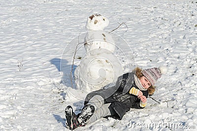 Little adorable girl child sculpts snowman from snow in winter Stock Photo