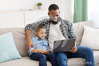 Little African Boy And Dad Watching Cartoons On Laptop Indoor Stock Photo