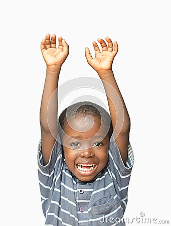 Little African boy holding his hands up in the air whilst laughing and smiling Stock Photo