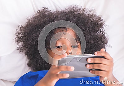 Little kid is playing with smartphone on bed Stock Photo