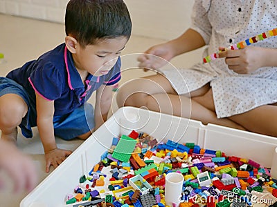 Little Asian baby being interested looking at colorful interlocking plastic bricks toy Stock Photo