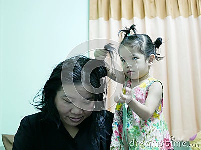 Little Asian baby girl giving her aunty`s hairs done Stock Photo