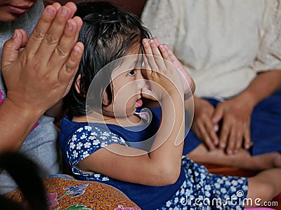 Little Asian baby girl paying respect, wai, to the elders during Rod Nam Dam Hua ceremony in Songkran festival in Thailand Stock Photo
