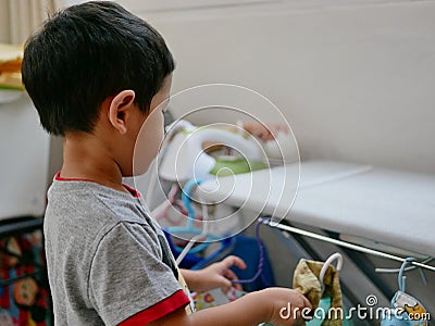 Little Asian baby putting the ironed shirt on the rack Stock Photo