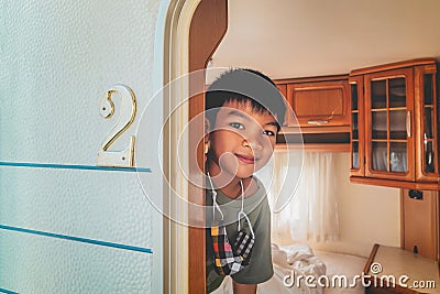 Little Asian Boy hiding behind a Caravan trailer home door waiting for parent to come home Stock Photo