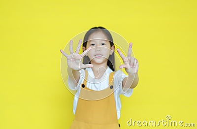 Little asian child girl showing finger number eight isolated on yellow background. Kid counting with fingers for education concept Stock Photo