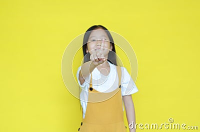 Little asian child girl showing finger number one isolated on yellow background. Kid counting with fingers for education concept. Stock Photo