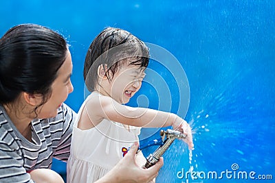 Little asian girl and mother play with water hose Stock Photo