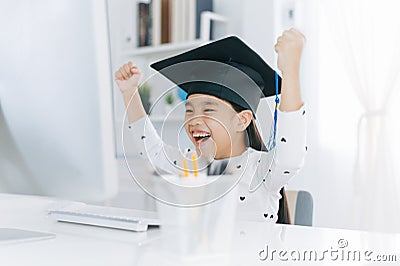 Little Asian girl wearing graduate hat doing homework and smile with happiness for success of education concept s Stock Photo