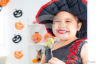 Girl in witch dress smiling and holding candy . Stock Photo