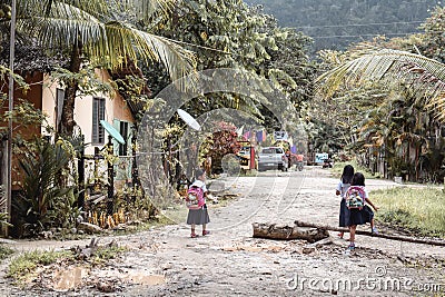 Little Asian school girls walking to school on a muddy road in a jungle conditions in Port Barton Palawan the Philippines Editorial Stock Photo