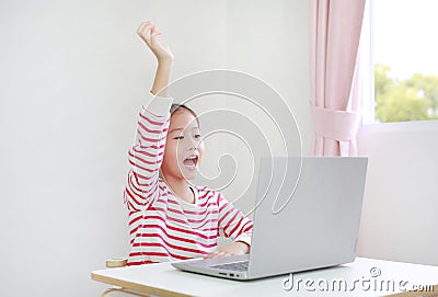 Little asian schoolgirl study online learning class by video call on laptop computer with teacher during new normal Covid-19 Stock Photo