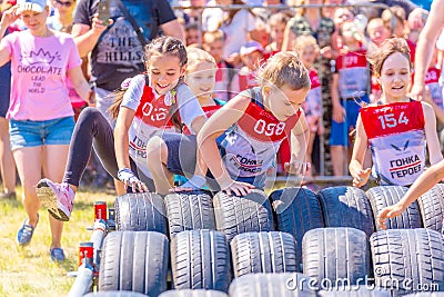 little athletes start in children`s races to overcome obstacles. Text in Russian: race of heroes, children`s start Editorial Stock Photo