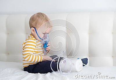 Little baby boy himself using steam inhaler nebulizer mask himself on the bed. copy space. health medical care. Stock Photo