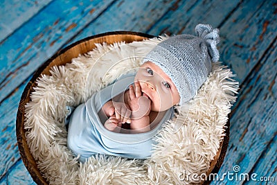 Little baby boy with knitted hat in a basket, happily smiling Stock Photo