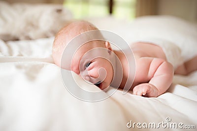 Little baby boy lying on bed making funny face, laughing. Stock Photo