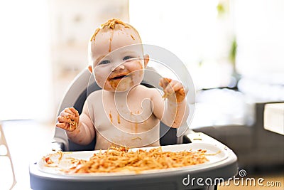 Little baby girl eating her spaghetti dinner and making a mess Stock Photo