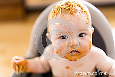 Little baby girl eating her spaghetti dinner and making a mess Stock Photo