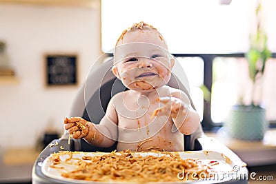 Little baby girl eating her spaghetti dinner and making a mess Stock Photo