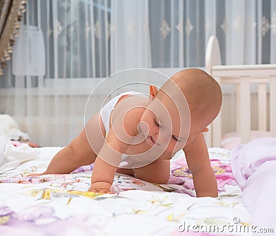 Little baby girl in a nappy crawling on a bed. Stock Photo