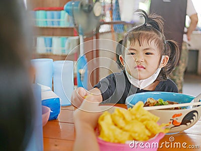 Little baby girl reaching her hand out for the same piece of deep fried wantan as taken by her older sister - sisters / siblings Stock Photo