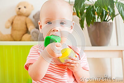 Little baby girl sitting on the floor, crawling and playing with brightly colored educational toys Stock Photo