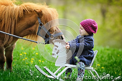 Little baby girl on wooden rocking horse and pony Stock Photo