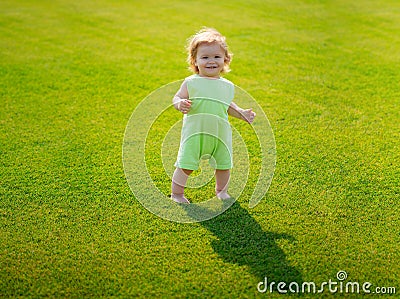 Little baby learning to crawl steps on the grass. Concept childrens months. Happy child playing on green grass Stock Photo