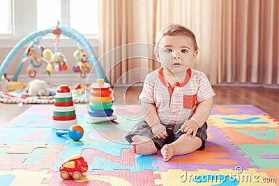 Little baby playing with toys on playmat at home. Stock Photo