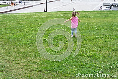 Little baby running on the grass against the background of a modern city Stock Photo