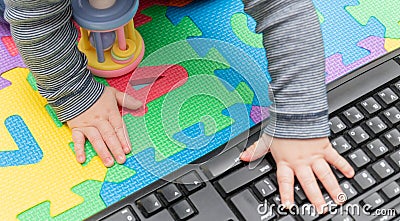 Little baby`s hands, on a computer mouse and keyboard - child development, getting familiar with technology since their early age Stock Photo