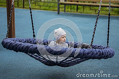 Little baby on spider web nest swing. Baby girl boy 1 year swinging on a swing Stock Photo