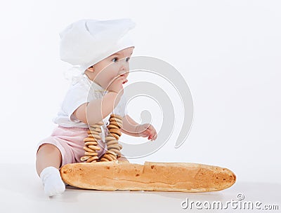 Little baker baby girl with a long loaf and bagels. Stock Photo