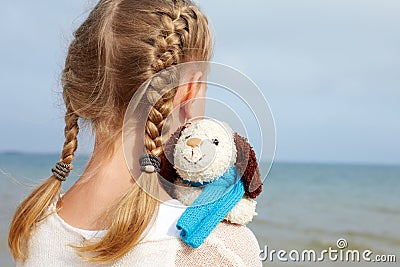 The little beautiful girl embraces an amusing dog - toy. Stock Photo