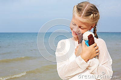 The little beautiful girl embraces an amusing dog - toy. Favorite soft toy. Stock Photo