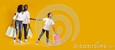 Little black girl and her parents walking holding shopper bags Stock Photo