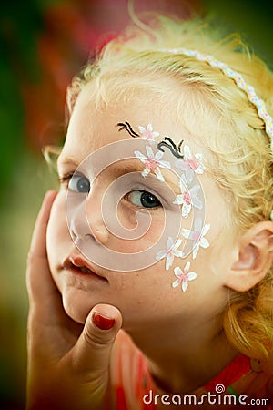 Little blond blue eyed girl face painting Stock Photo