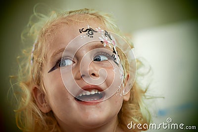 Little blond blue eyed girl face painting is smiling Stock Photo
