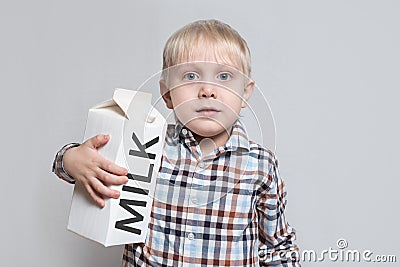 Little blond boy cuddles a large white carton milk package. Light background Stock Photo