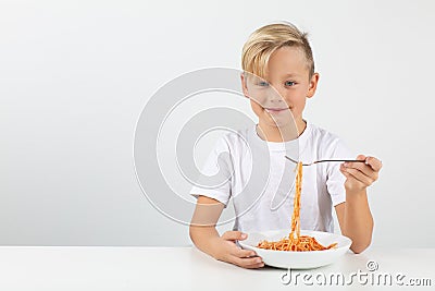 Little blond boy eats spaghetti and smiles Stock Photo