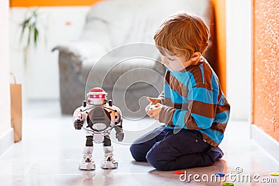 Little blond boy playing with robot toy at home, indoor. Stock Photo