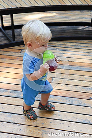 Little blond child infant drinking juice on the playground Stock Photo