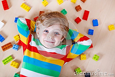 Little blond child playing with lots of colorful plastic blocks Stock Photo