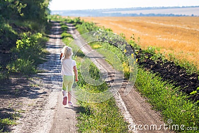 Little blond girl running along dirt rural road Editorial Stock Photo