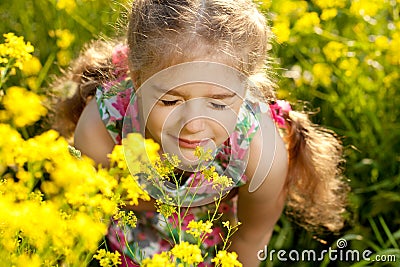 Little blonde girl inhales scent of flowers Stock Photo