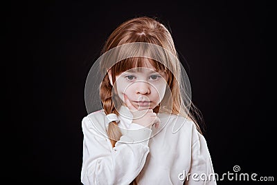 Little blonde girl looking thoughtfully down finger on cheek Stock Photo