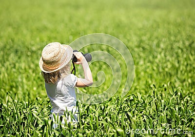 Little blonde girl in straw hat looking through binoculars Stock Photo